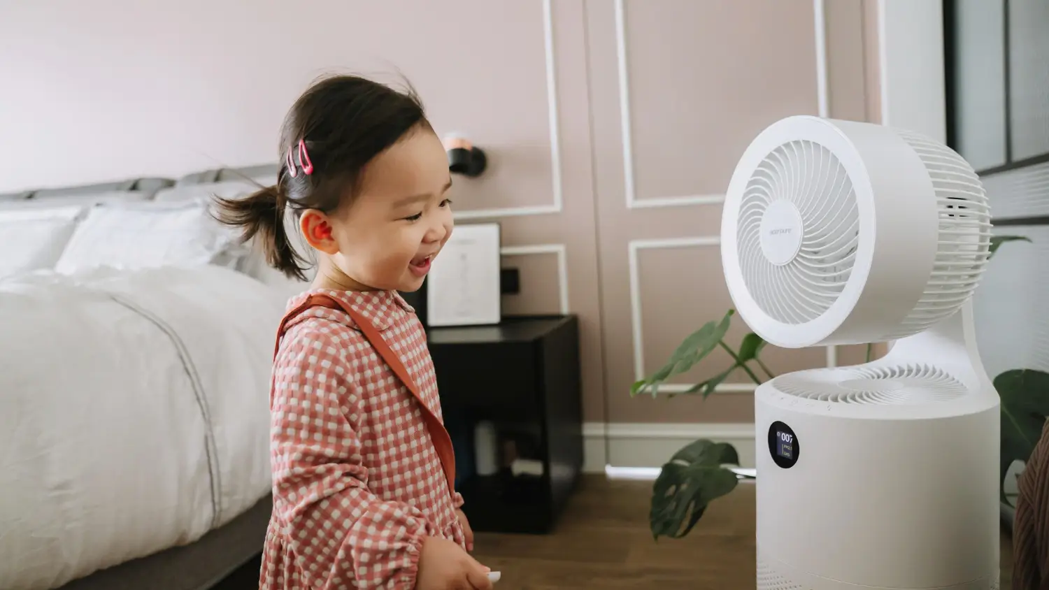 A young Asian child smiling in front of an Acerpure fan