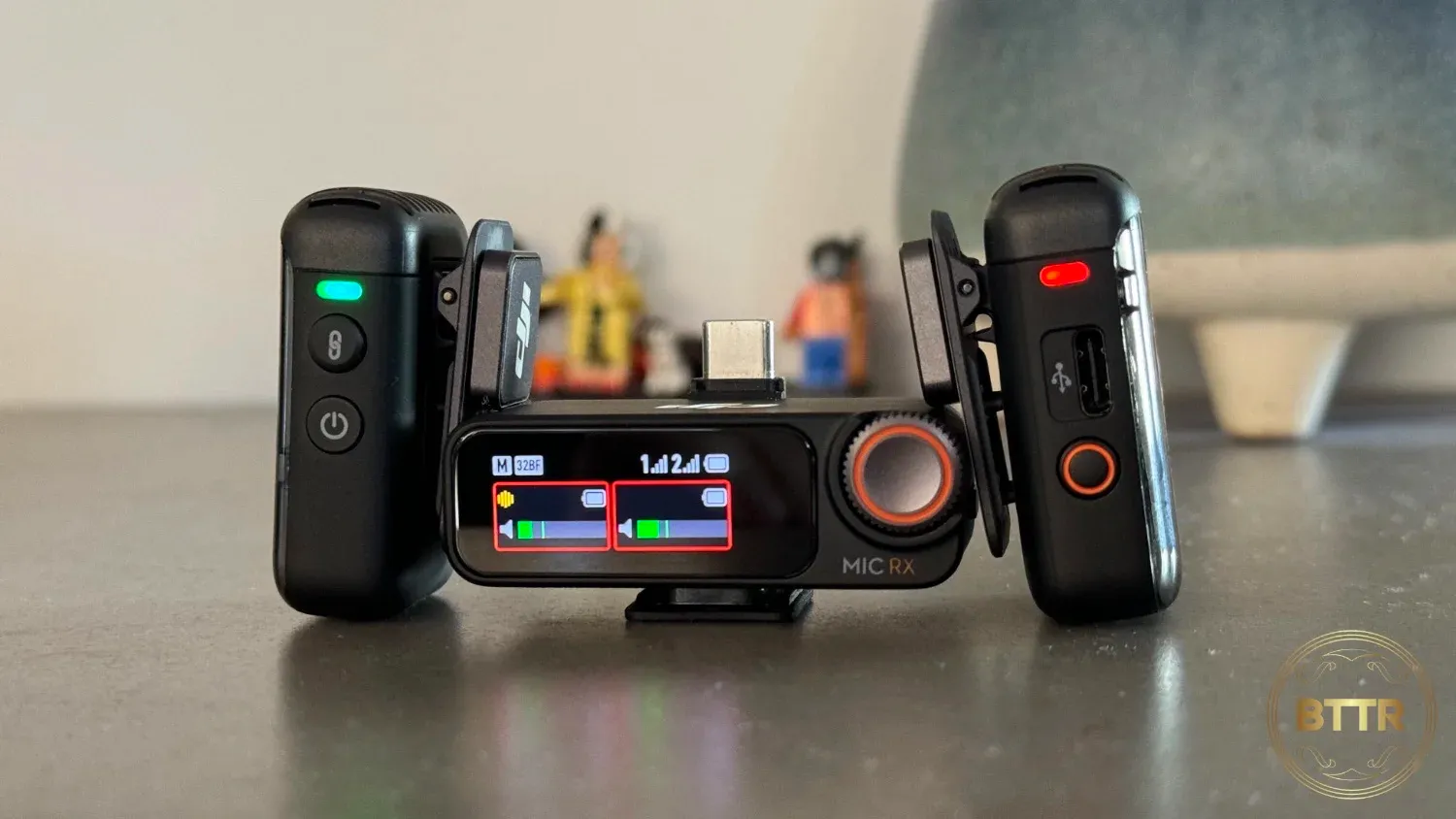 The 2 transmitters resting next to the receiver of the DJI Mic 2