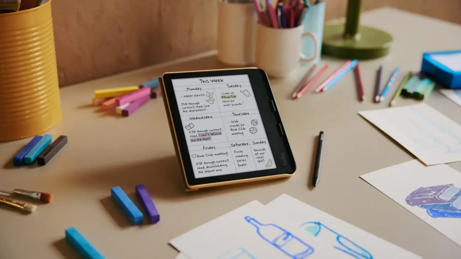 The Kobo Libra Colour on a desk surrounded by pencils and crayons