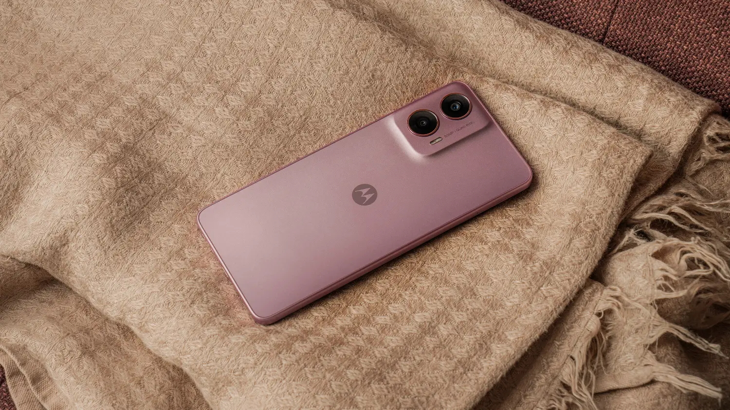 A pink Moto G24 on a beige throw rug