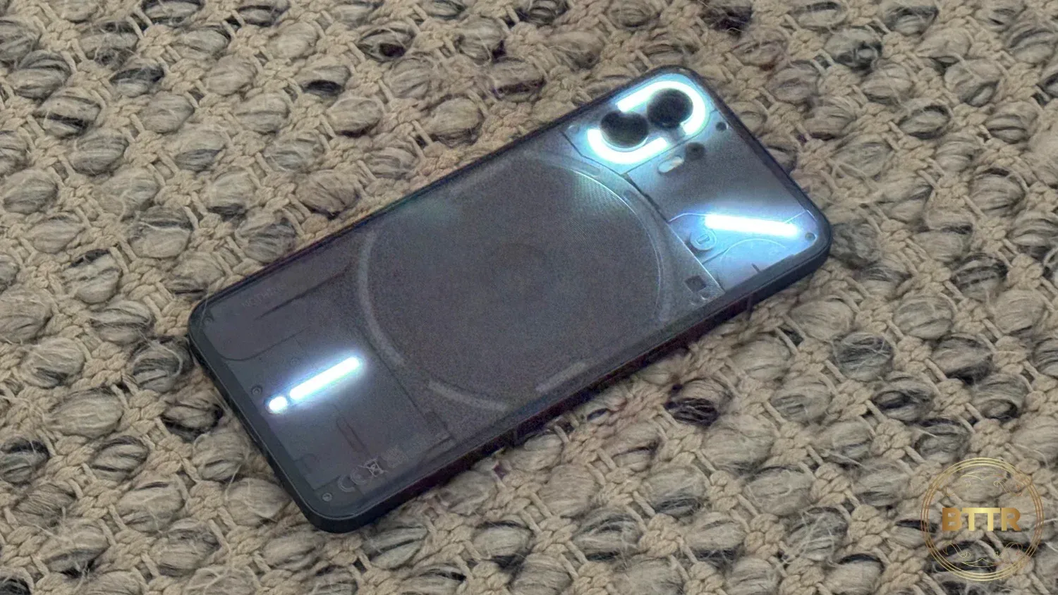 Glyphs flashing on the Nothing Phone (2) as it sits on a rug