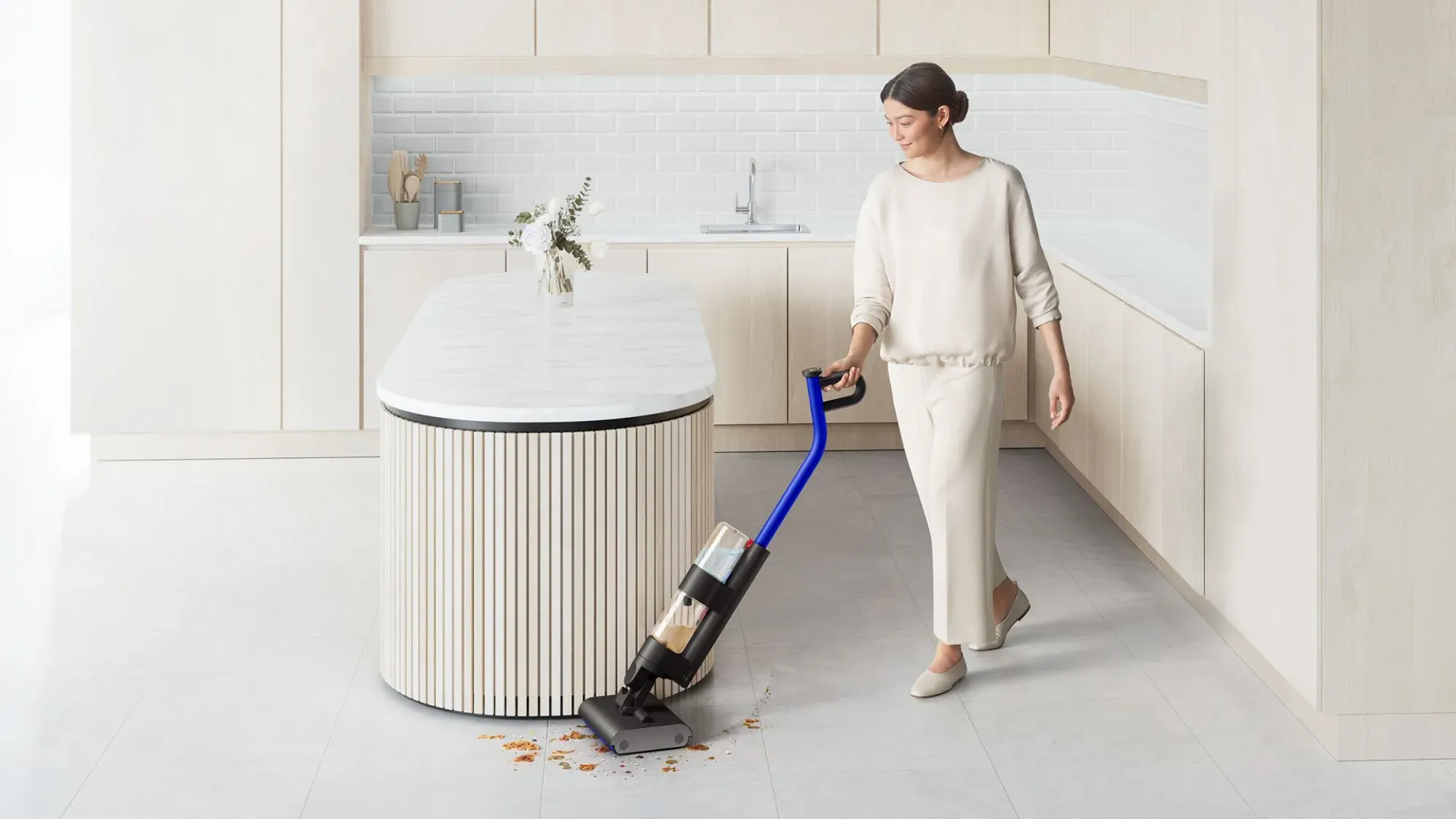 A woman washing the floor around a pristine kitchen island bench