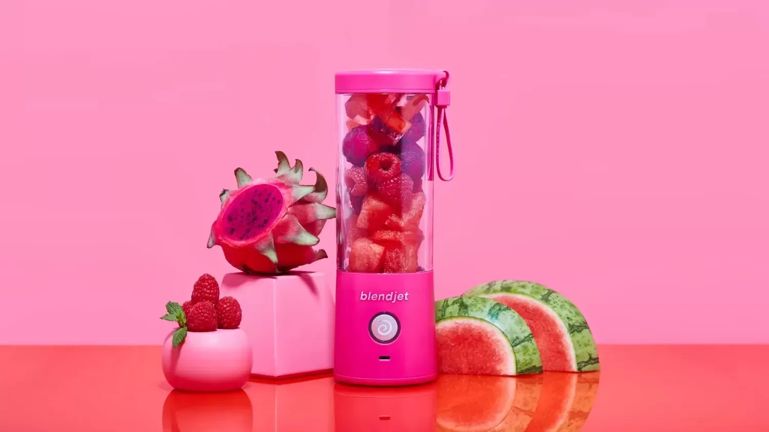 A pink portable blender with pink food and a pink background