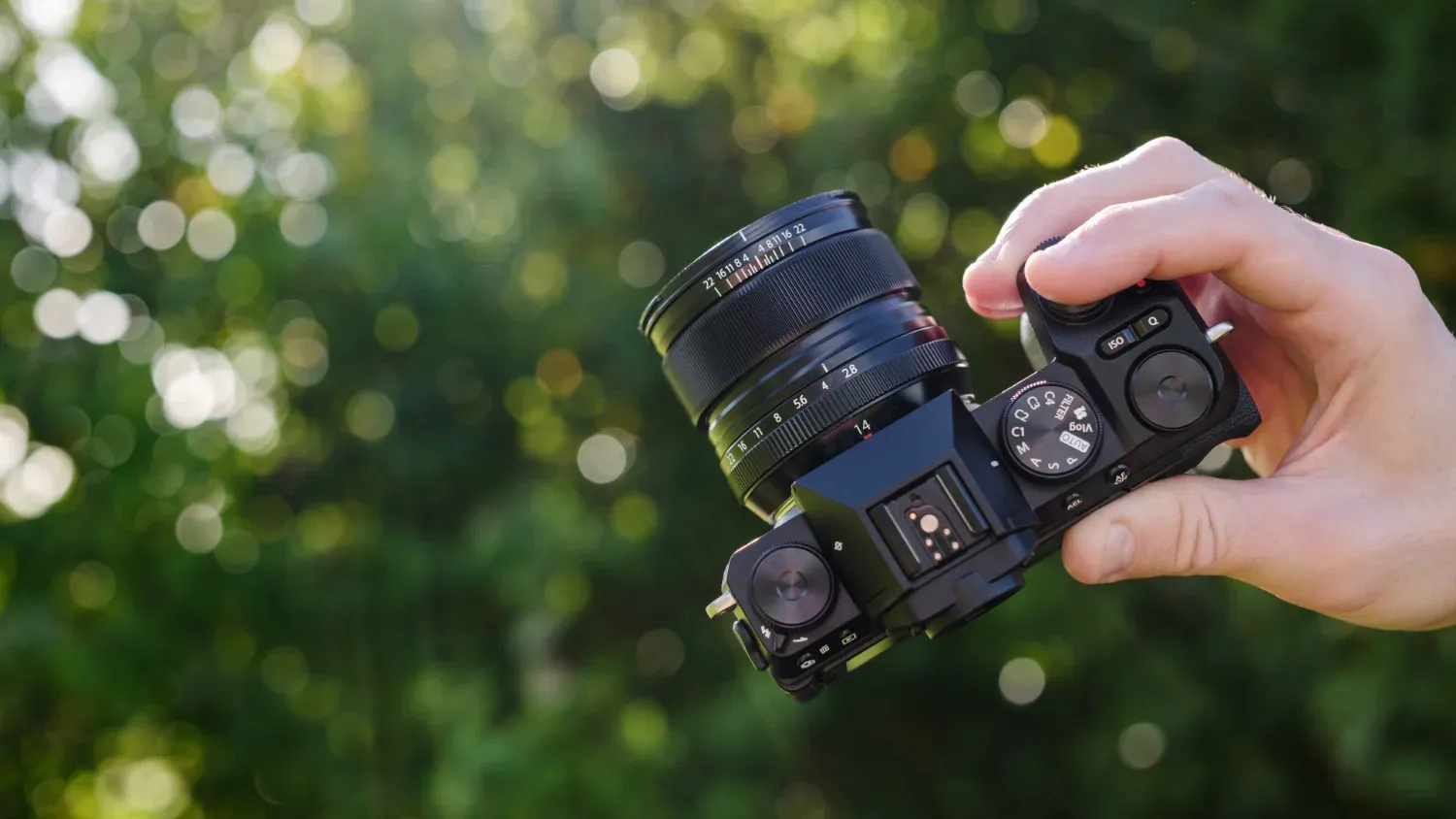 A hand holding the Fujifilm X-S20 , looking at the top of the camera 