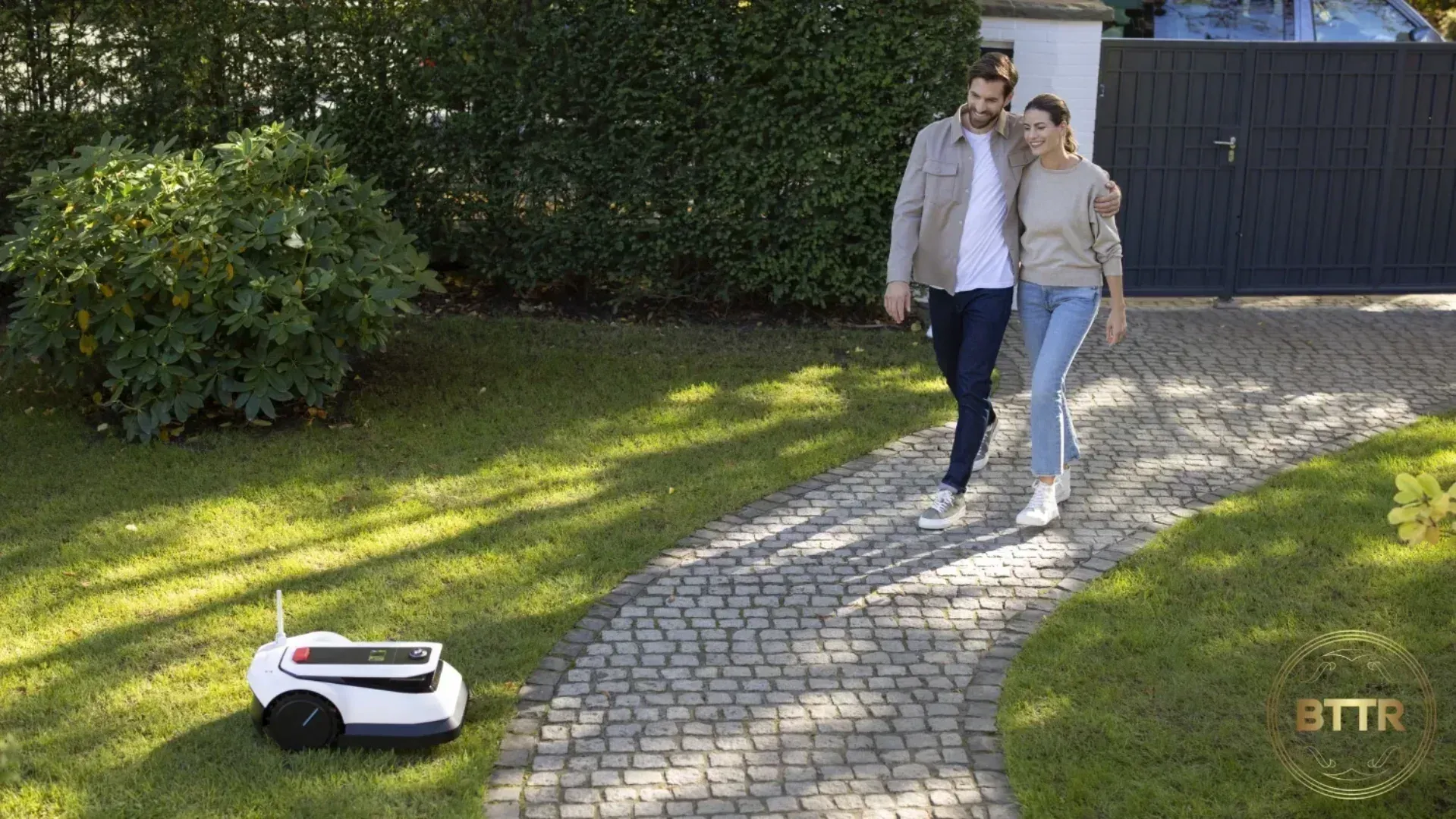 Ecovacs Goat G1 lawnmower doing its thing while a couple walk arm in arm along a path