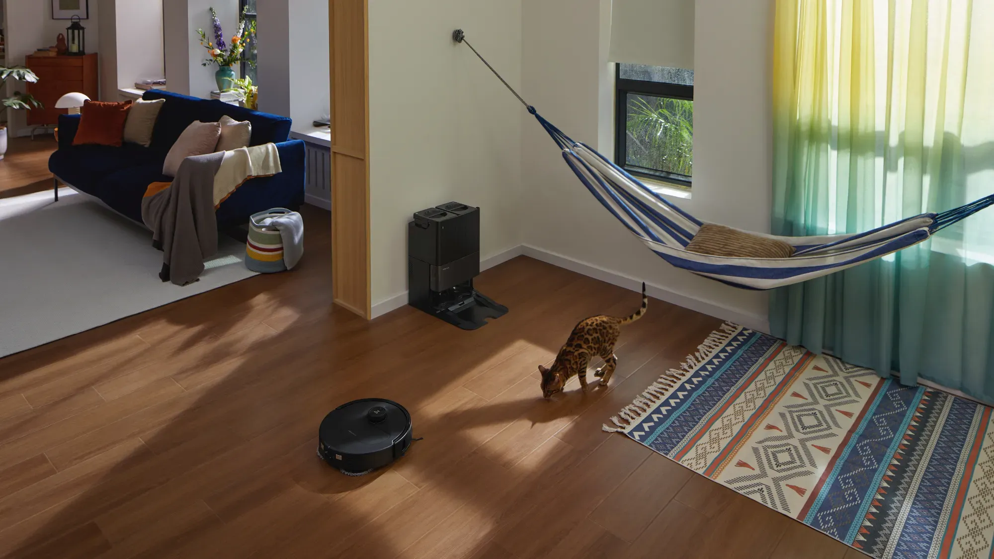 A weird room with a hammock hanging above a rug while the Qrevo Master cleans nearby