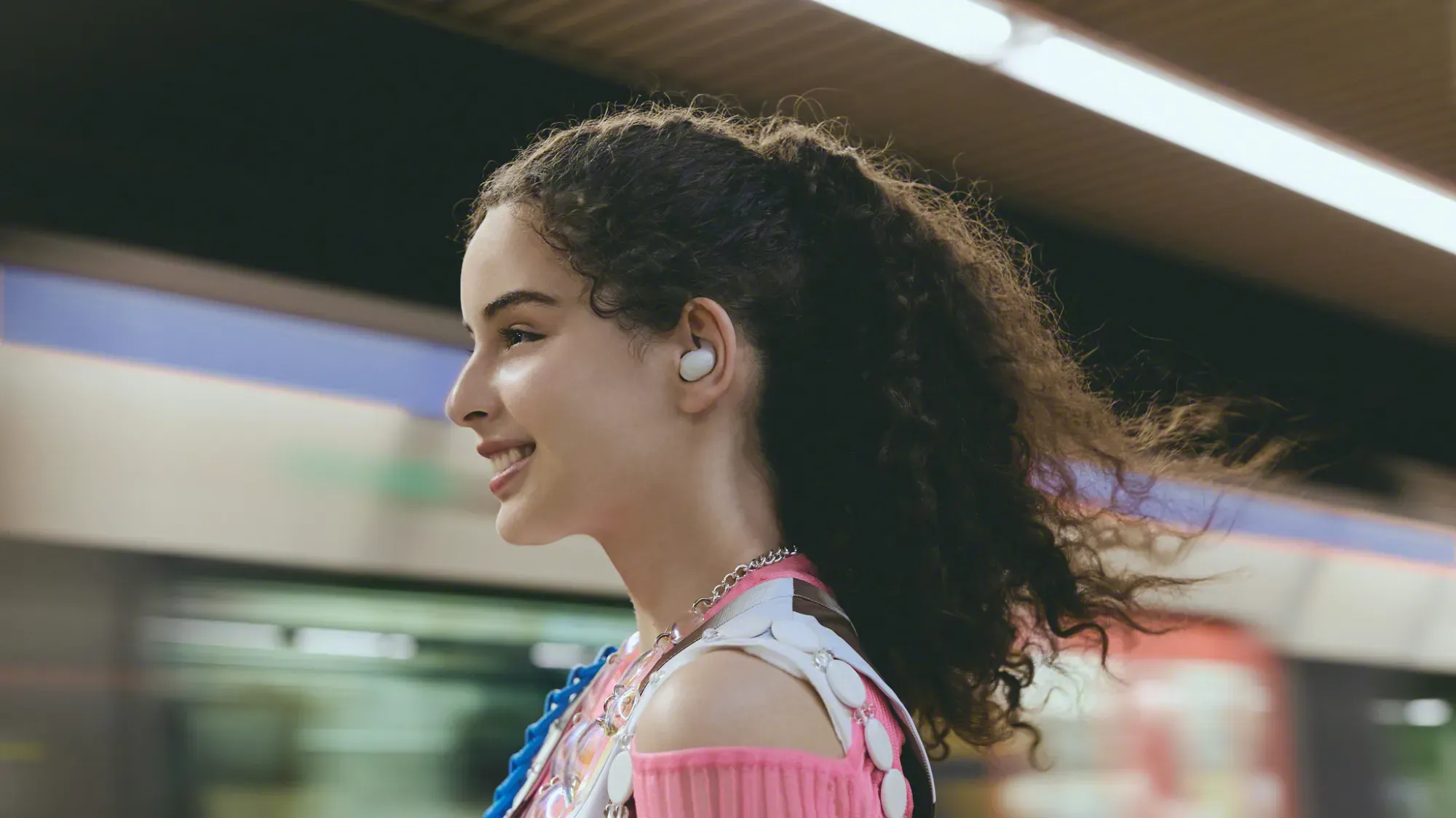 A young woman wearing LinkBuds Fit at a train station