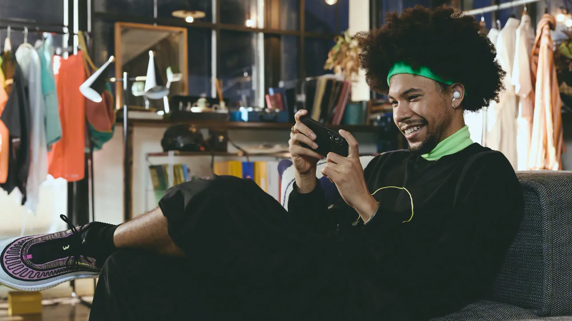 A young man playing games on his phone while wearing the LinkBuds Open