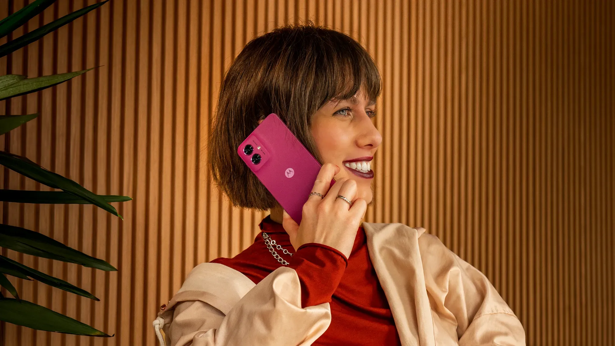 A woman holding the pink G55 to her ear