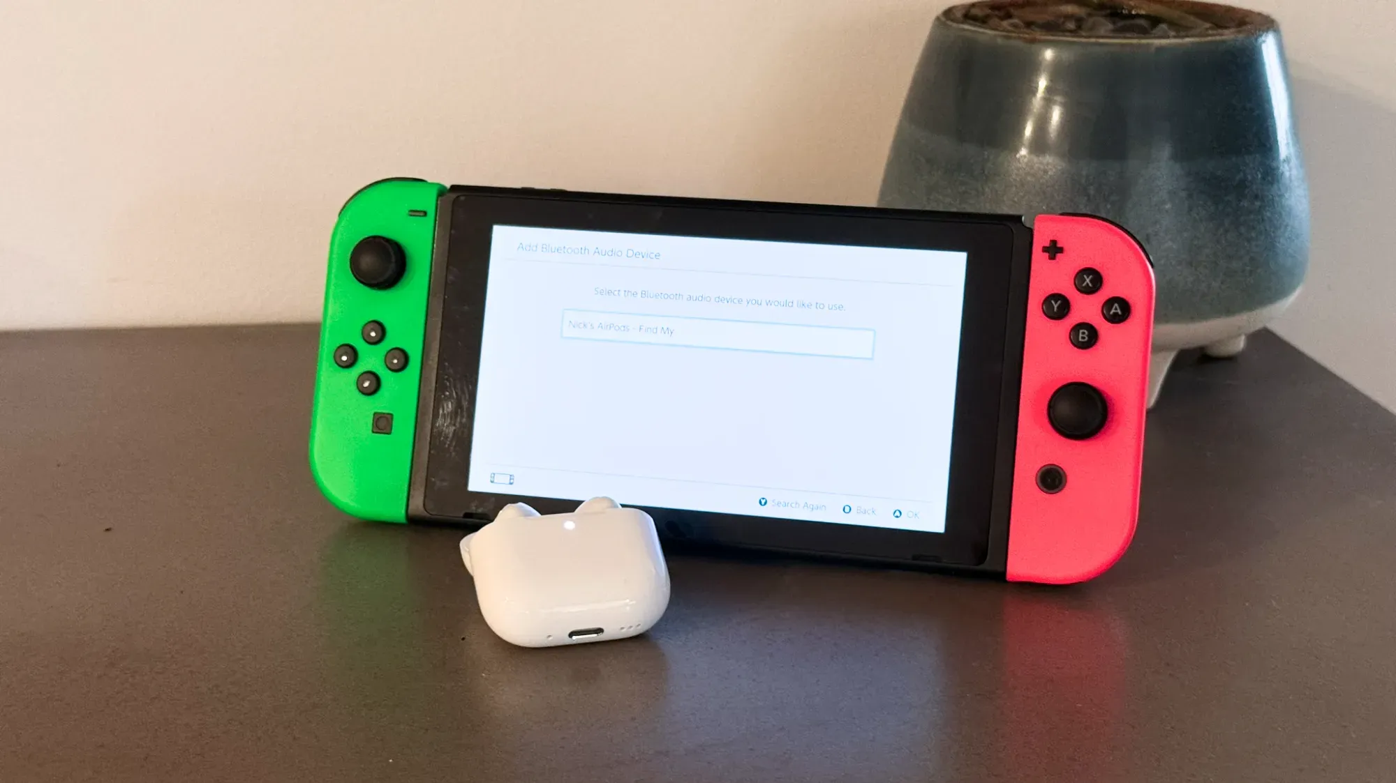 The AirPods 4 in front of the Nintendo Switch in pairing mode.