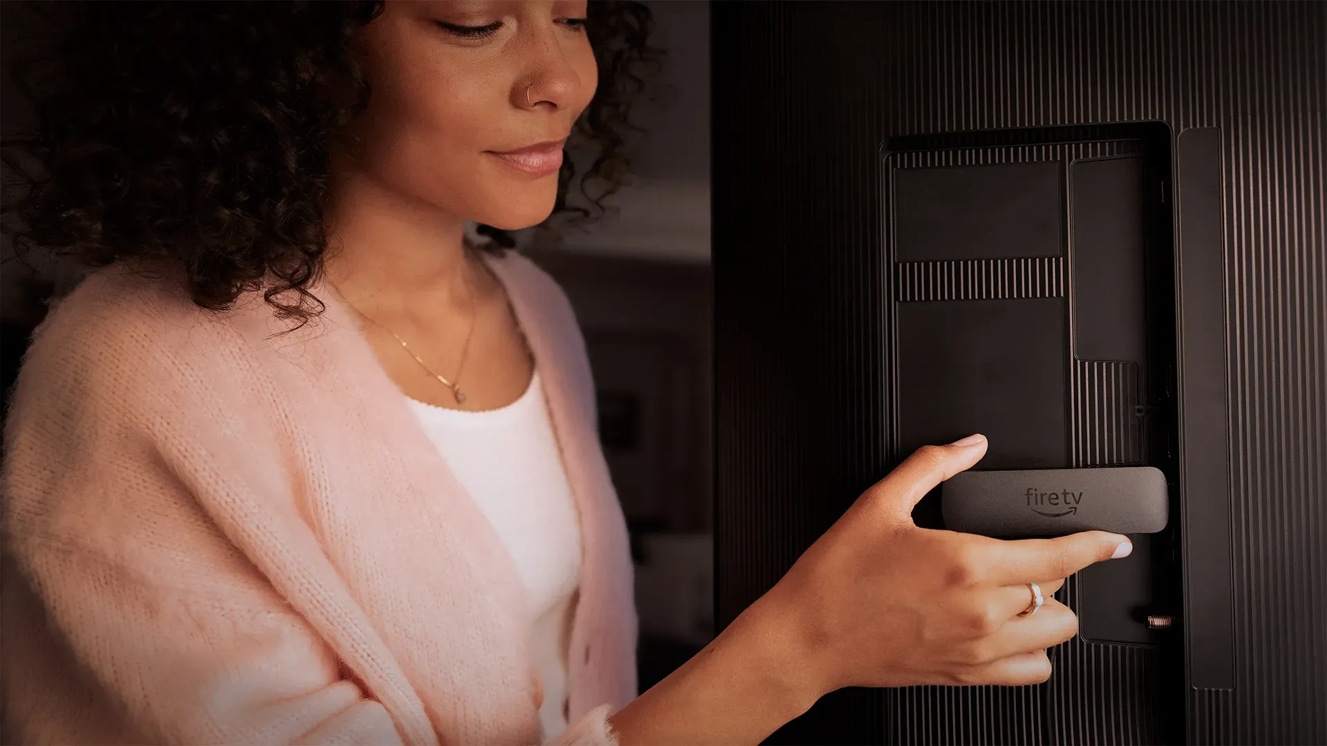 A woman inserting the Fire TV stick into a TV