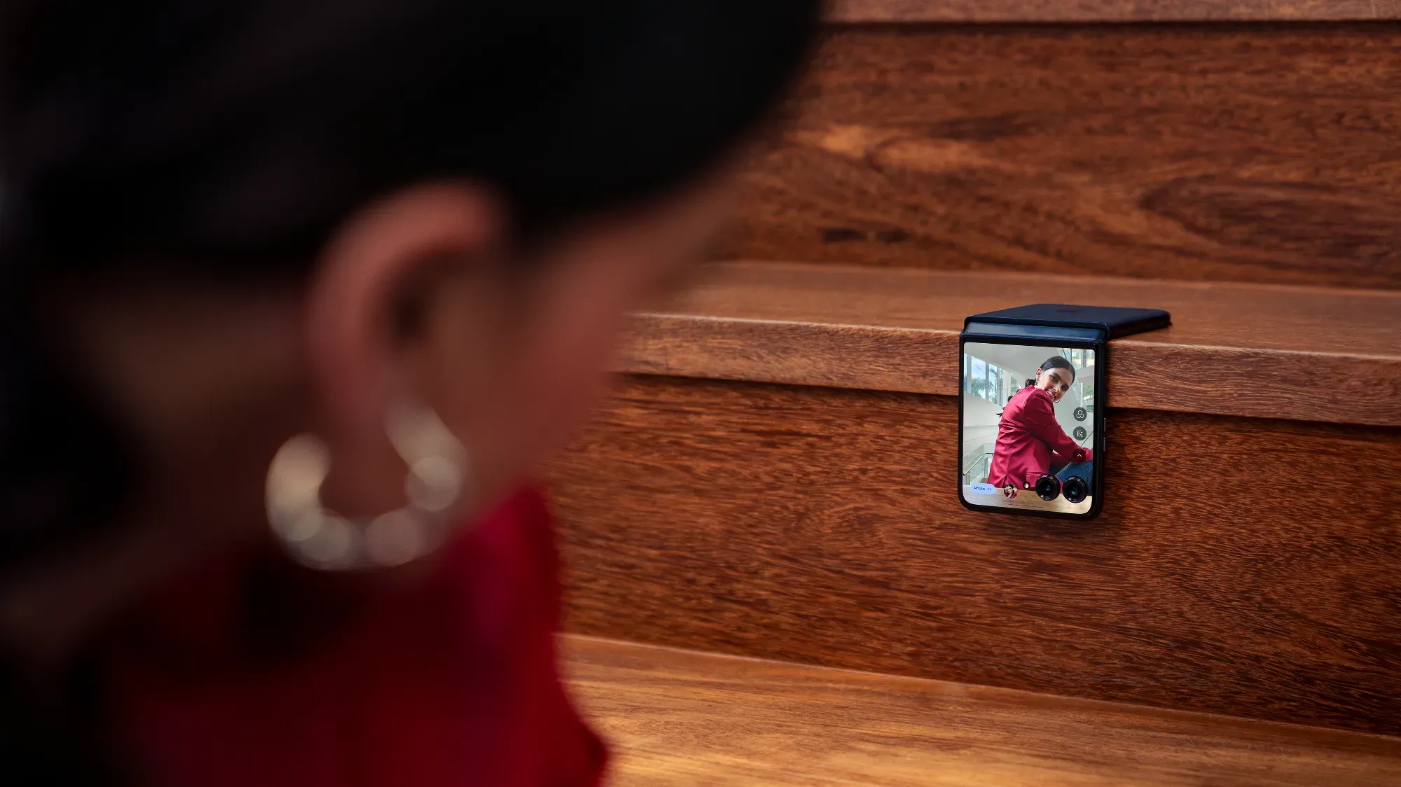 A Moto razr 50 ultra on the stairs showing the reflection of a woman taking a selfie