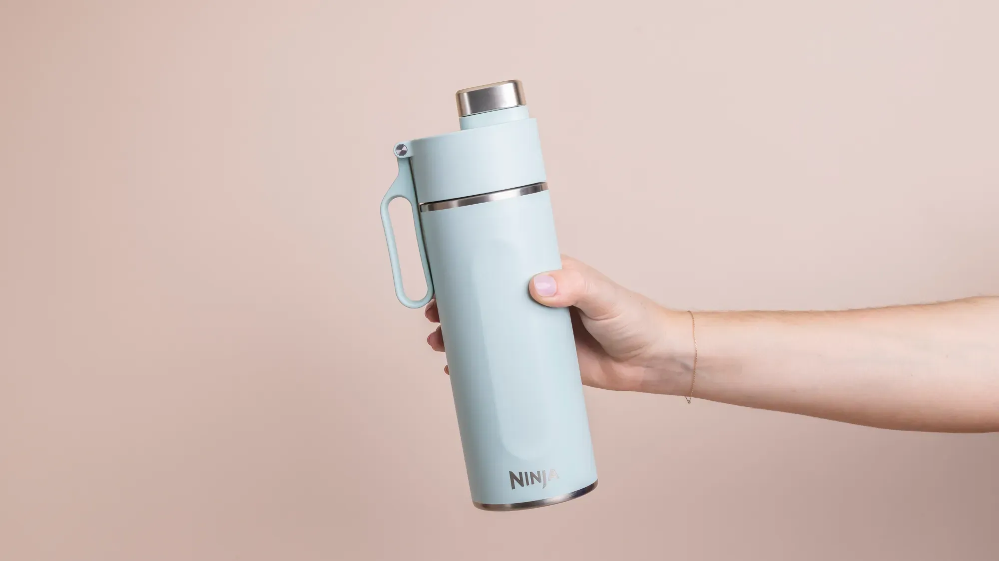 A hand holding the Ninja Thirsti travel mug