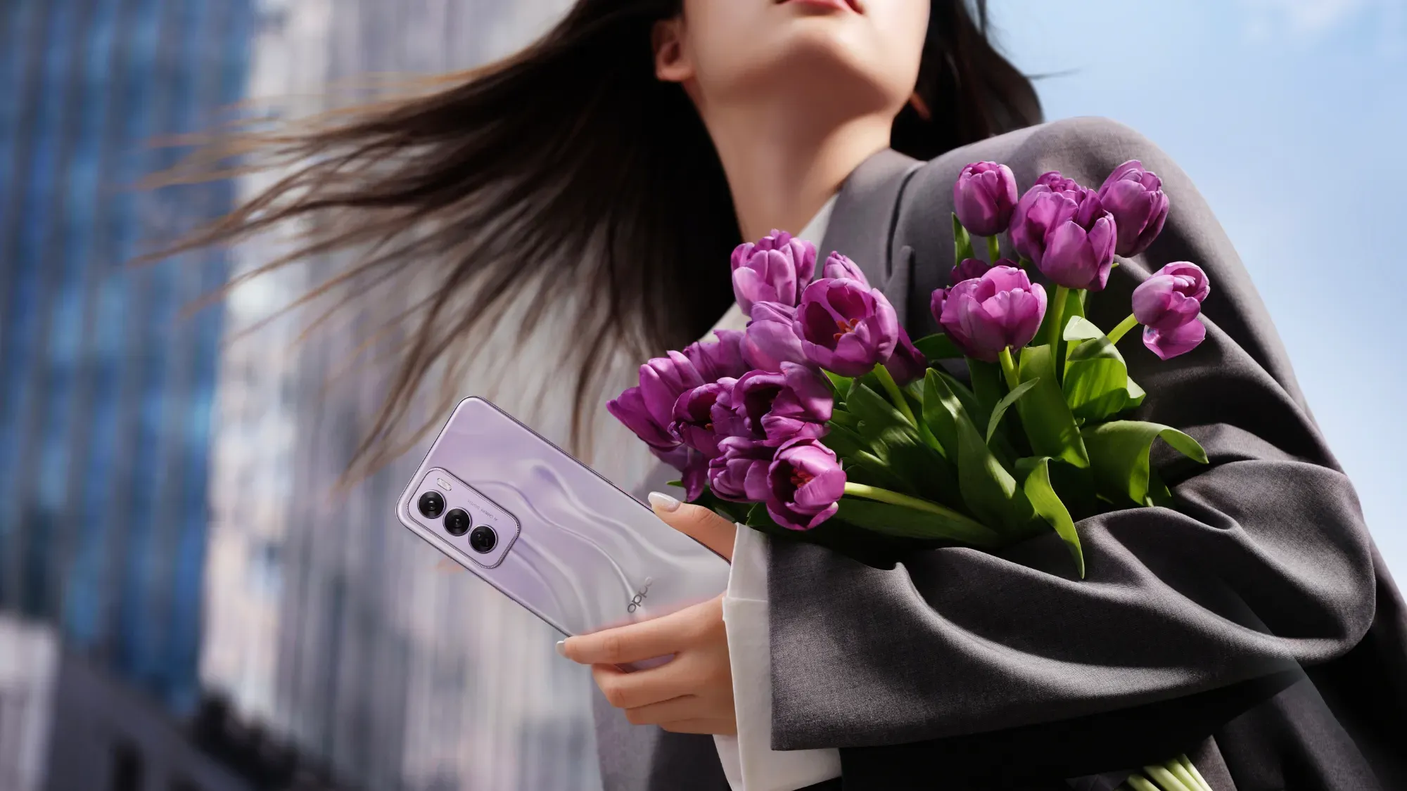 A woman holding the OPPO Reno12 Pro and a bunch of flowers