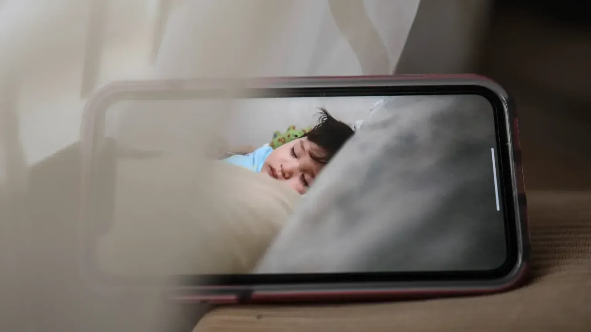 A baby being watched on a phone screen via a baby monitor