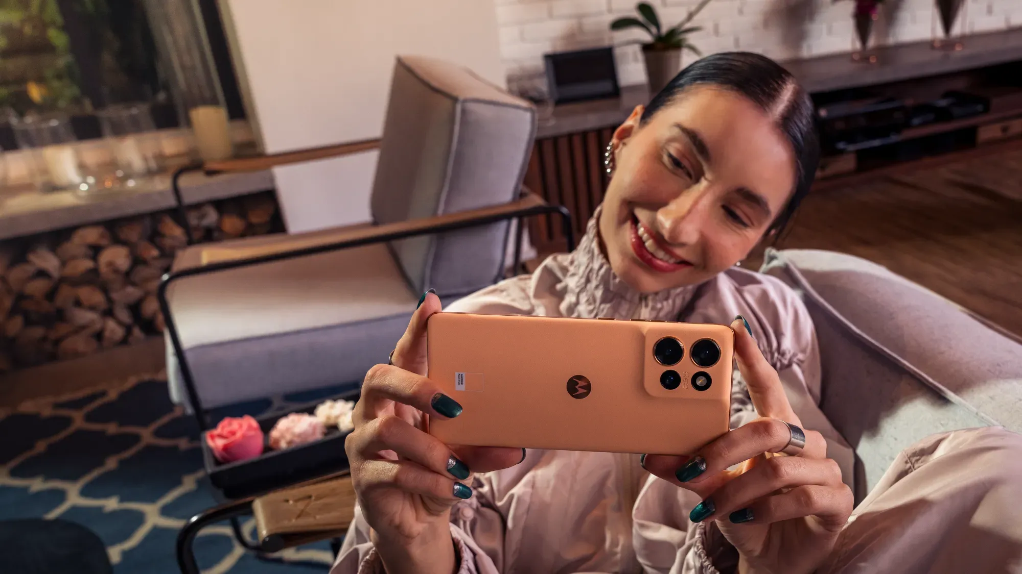 A woman holding the Edge 50 in Peach Fuzz and smiling