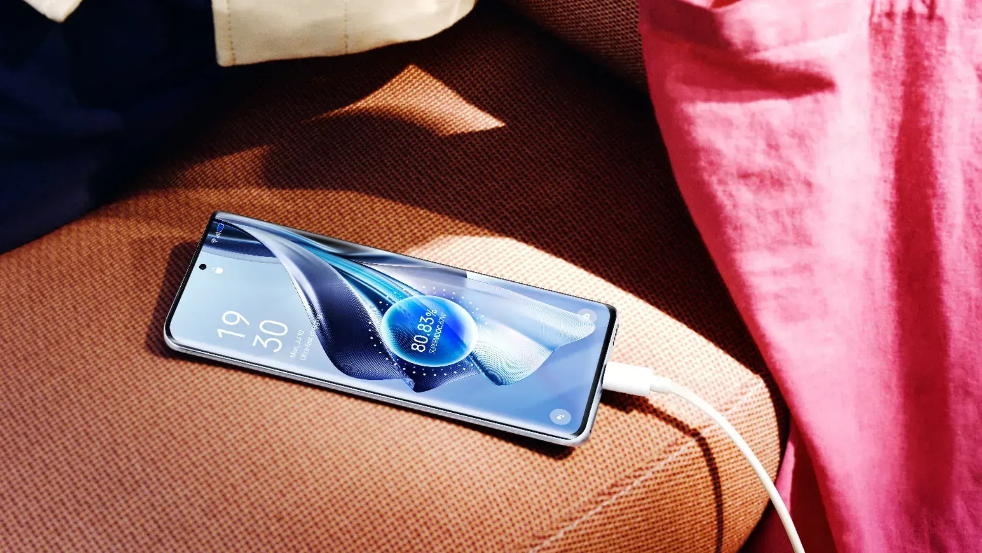 The Oppo Reno10 5G smartphone charging on a couch.