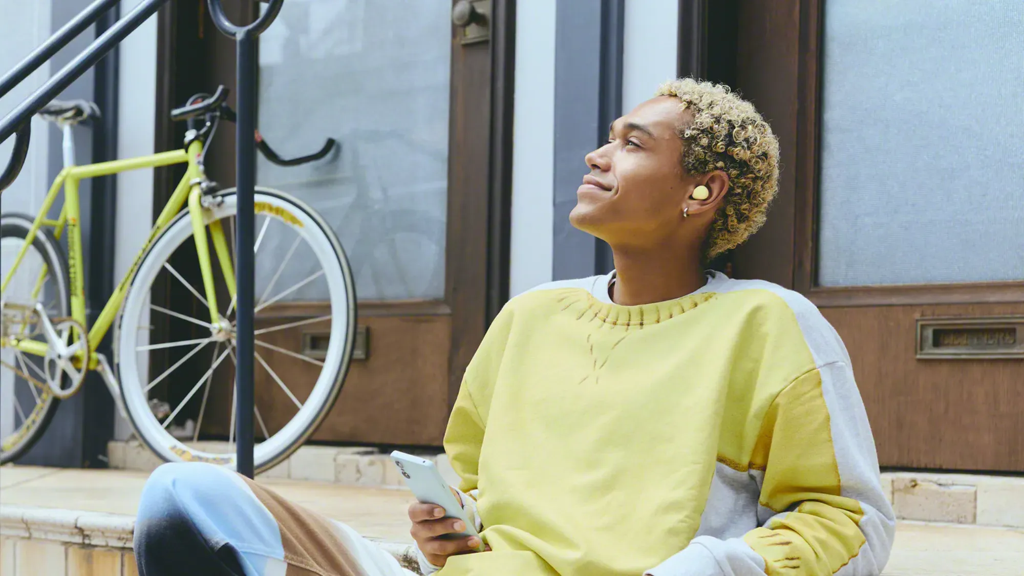 A man in a yellow and white jumper with a yellow pair of WF-C510 earbuds in.