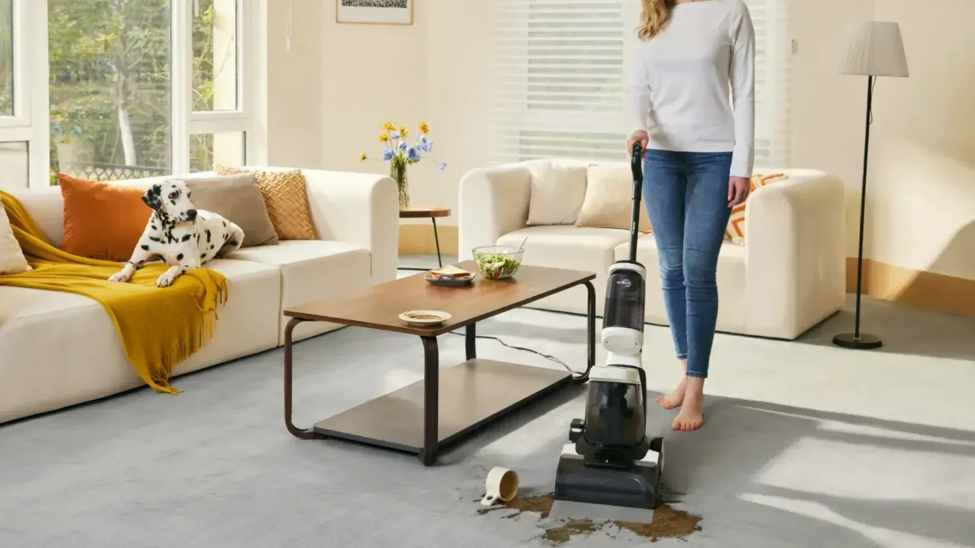 Tineco iCarpet washing coffee off a carpet while a dog sits on the lounge nearby