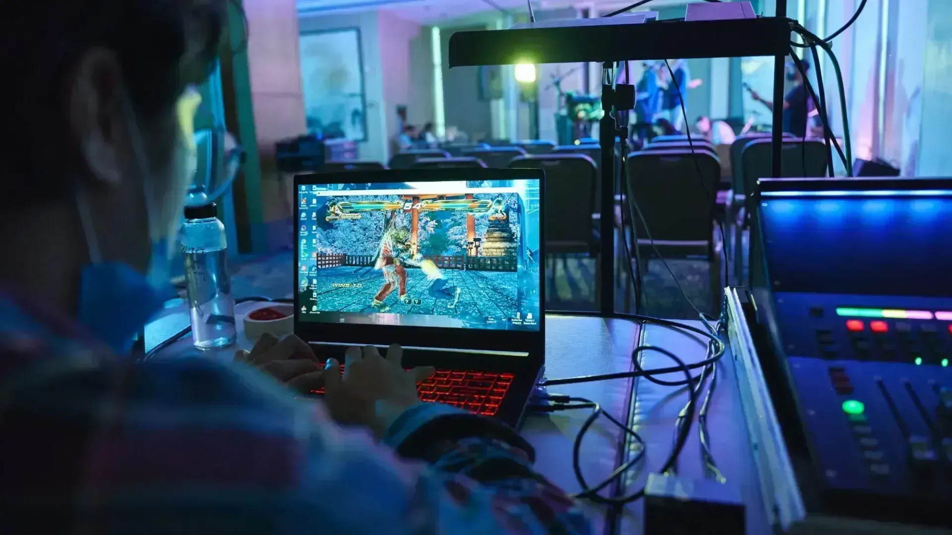 Man playing a gaming laptop at a table in a room.