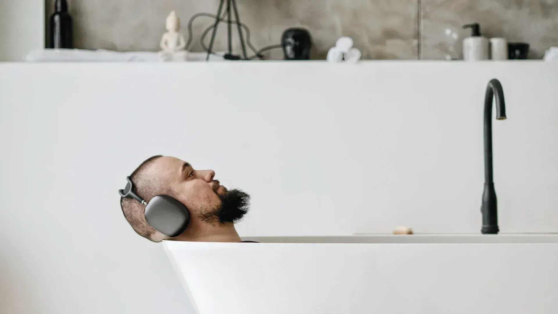 Man in bath wearing one of the best headphones in Australia