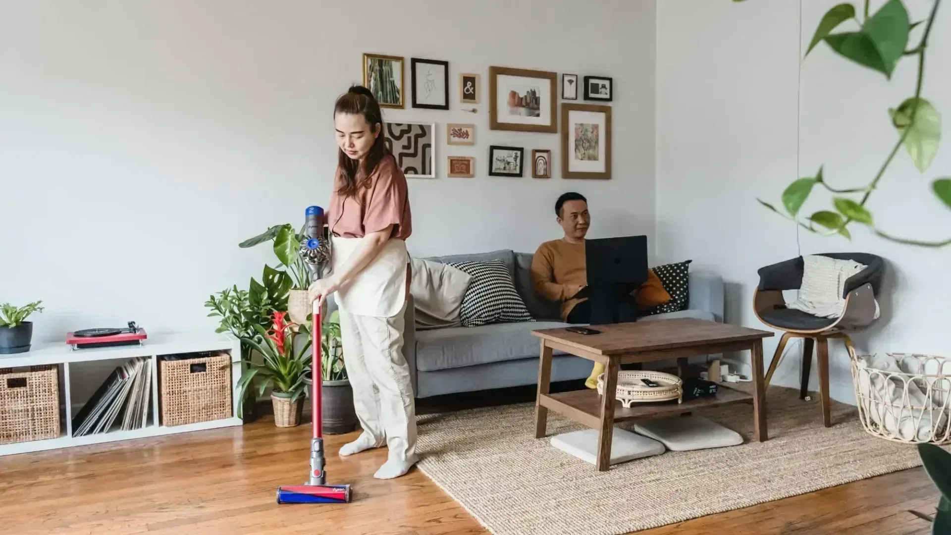 Woman vacuuming the floor with a stick vacuum cleaner