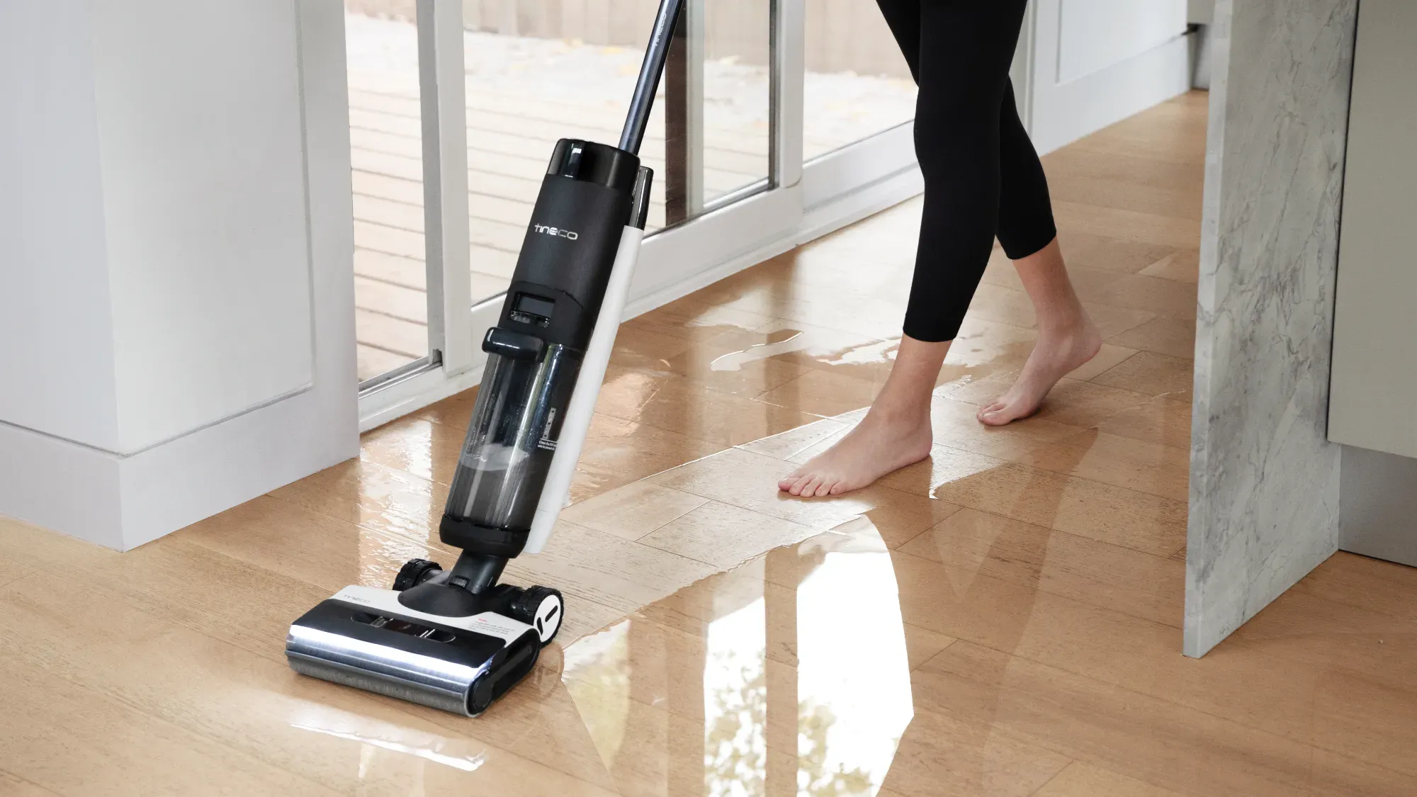 A woman mopping the floor with the S7 FlashDry while walking behind it barefoot