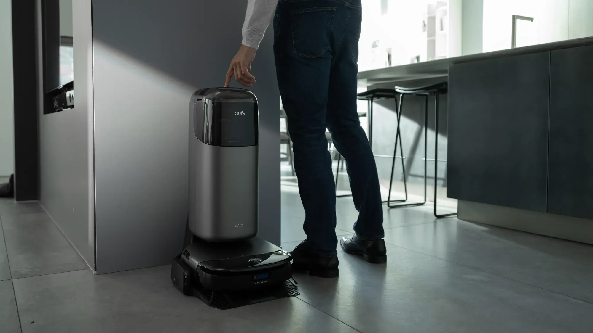 A man next to the Eufy S1 Pro in its base station in a dark kitchen area.