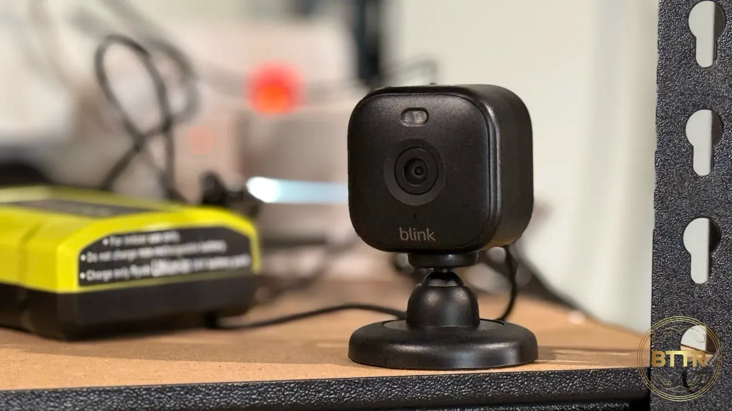 Blink Mini 2 on a shelf in a garage with cables and chargers