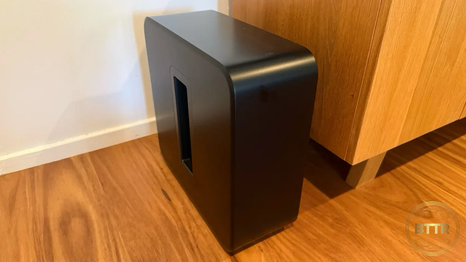 The Sonos Sub 4 sitting next to an entertainment unit