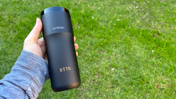 The Ember Travel Mug 2+ in hand over grass