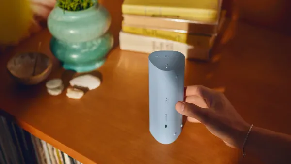 The Sonos Roam 2 in blue being held over a desk