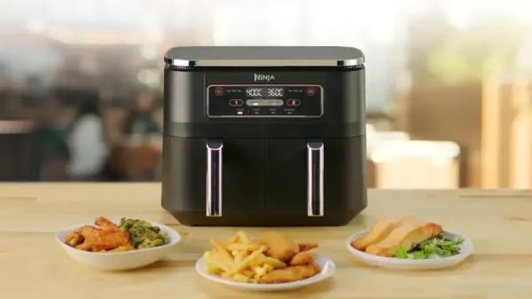 A Ninja air fryer on a bench with three plates of food in front