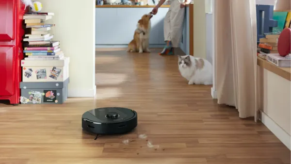 The Roborock Q5 Pro vacuuming pet hair with a cat watching suspiciously.