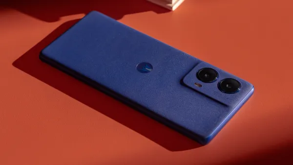 The Moto g85 in Cobalt Blue on an orange desktop