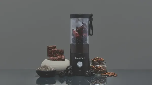 A black blender surrounded by dark foods and a dark background