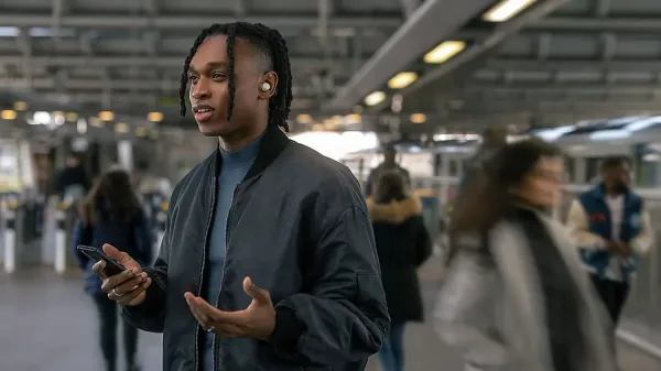 Man wearing the WF-1000XM5 earbuds at a train station