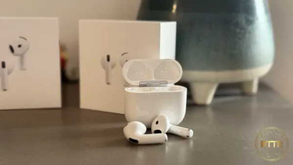 The Apple AirPods 4 with ANC in front of the box and a pot plant