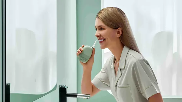 A woman using the Oclean A10 water flosser