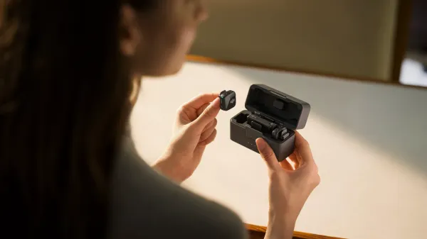 A woman pulling out one of the mic mini transmitters from the charging case