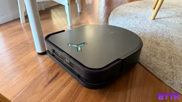 The Deebot X5 Pro Omni vacuuming hard floor next to a rug