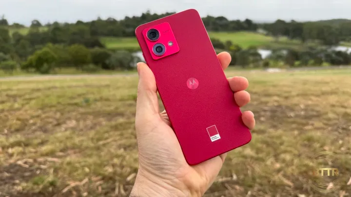 The Moto G84 in hand in front of a rugged AUstralian landscape