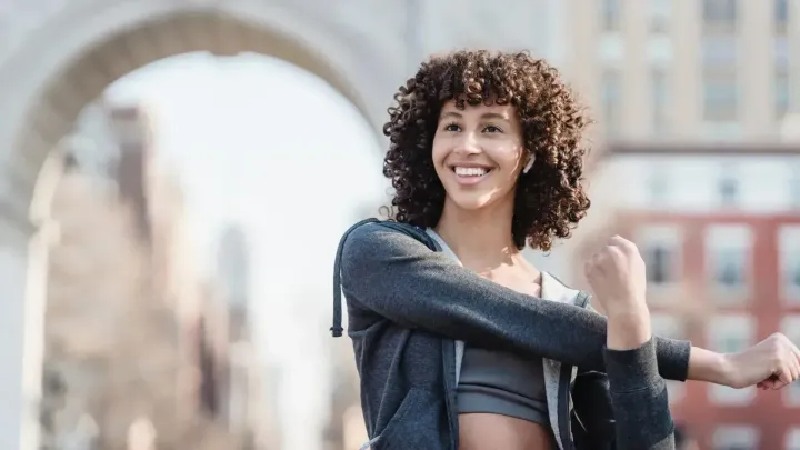 Young woman stretching while wearing wireless earbuds