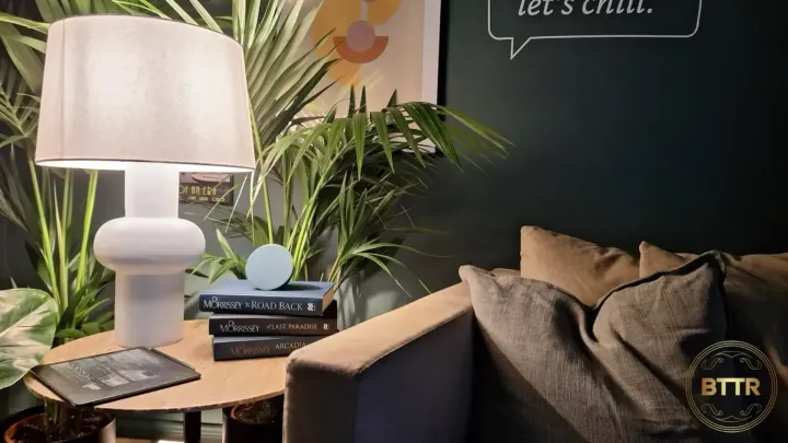 The Amazon Echo Pop on a pile of books on a lamp table in a reading room