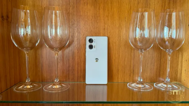 The Moto Edge 50 Fusion on a shelf between wine glasses